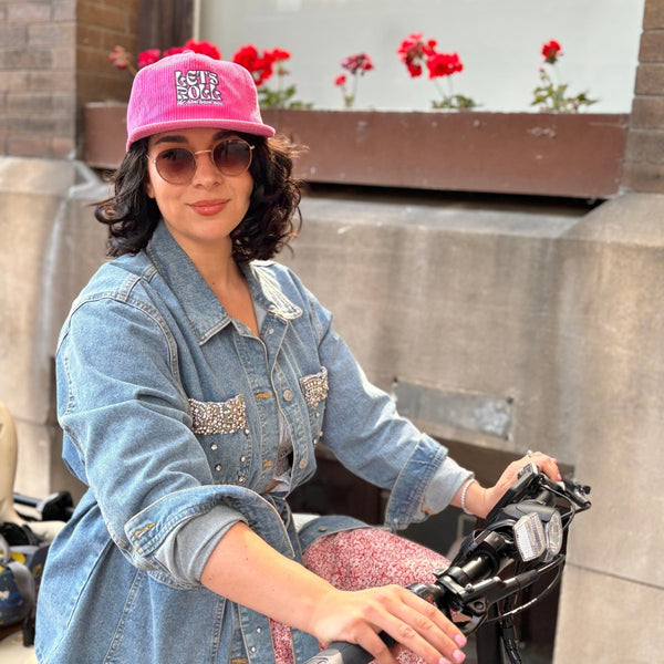 A person is wearing a pink corduroy baseball  hat with the words