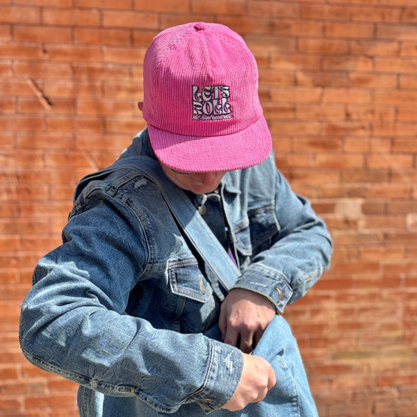 A person is wearing a pink corduroy baseball  cap with the words