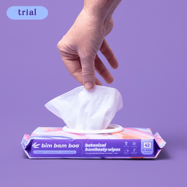 Hand pulling a wipe from bim bam boo package on purple background.