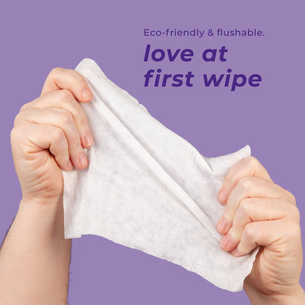 Hands holding a flushable wipe with text 'Eco-friendly & flushable. love at first wipe' on a purple background.