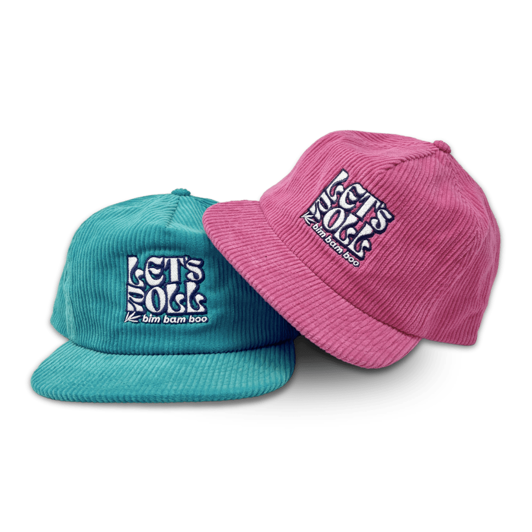 Close up of two corduroy baseball  hats with the words "Let's Roll" embroidered on them. One hat is a teal color, and the other hat is a pink color. 